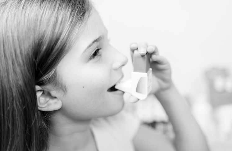 Junges Mädchen mit chronischem Asthma nutzt ein Asthmaspray, um das Atmen zu erleichtern. 